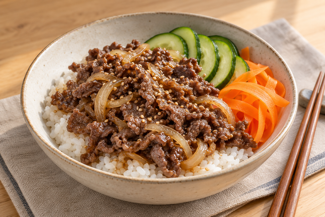Mild beef bulgogi with onion over rice, served with cucumber slices, carrot ribbons and sesame seeds